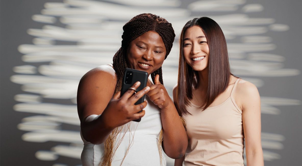 Two Women Looking at Phone - List Image